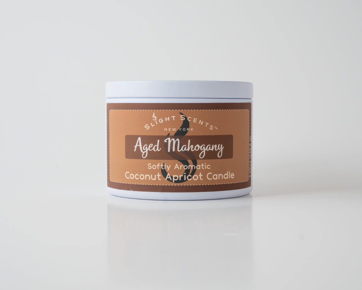Aged Mahogany Coconut Apricot Candle By SlightScents New York in a white metal tin on a white background.
