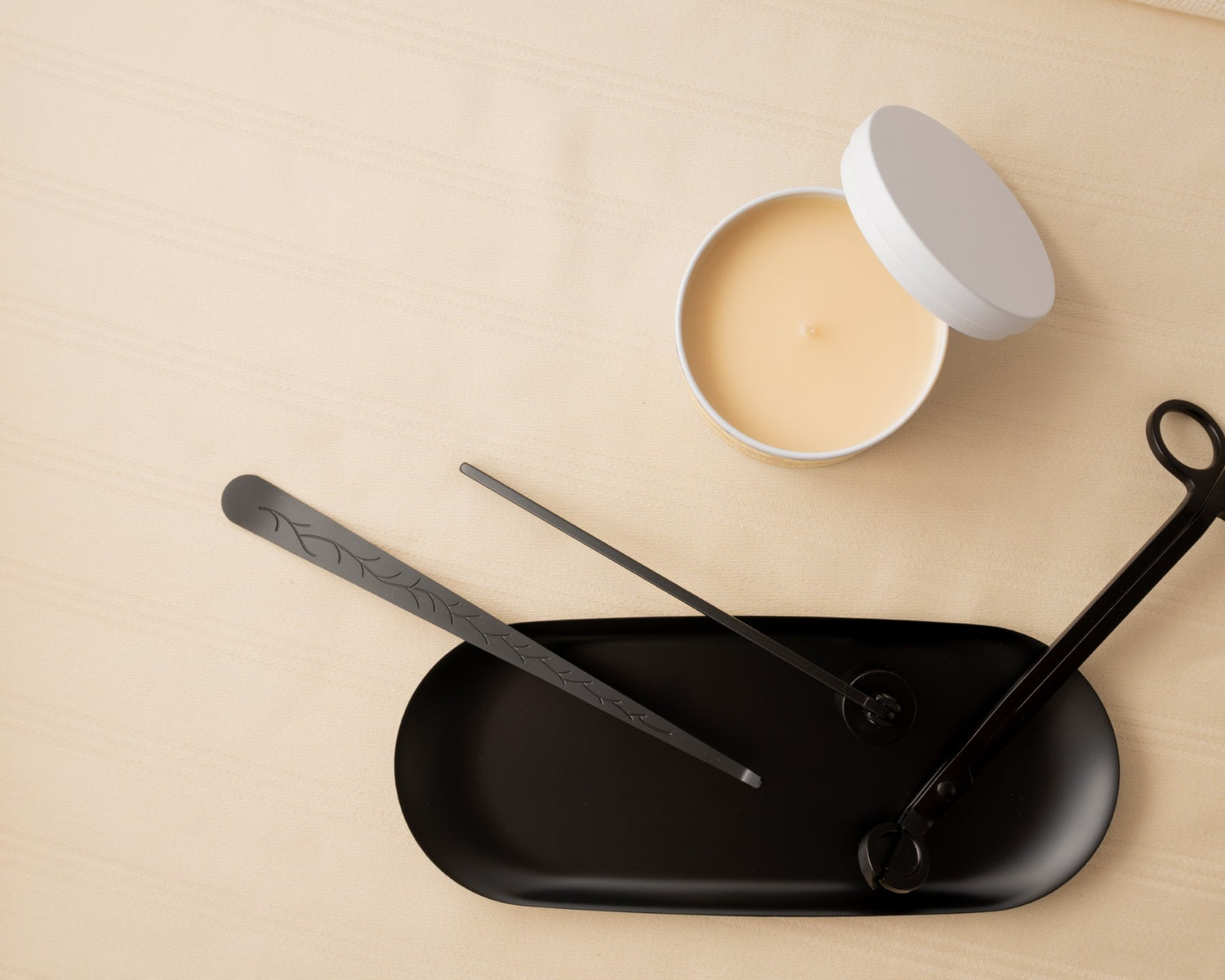 Cocoa Butter Vanilla Candle with its lid off next to a black candle care kit.