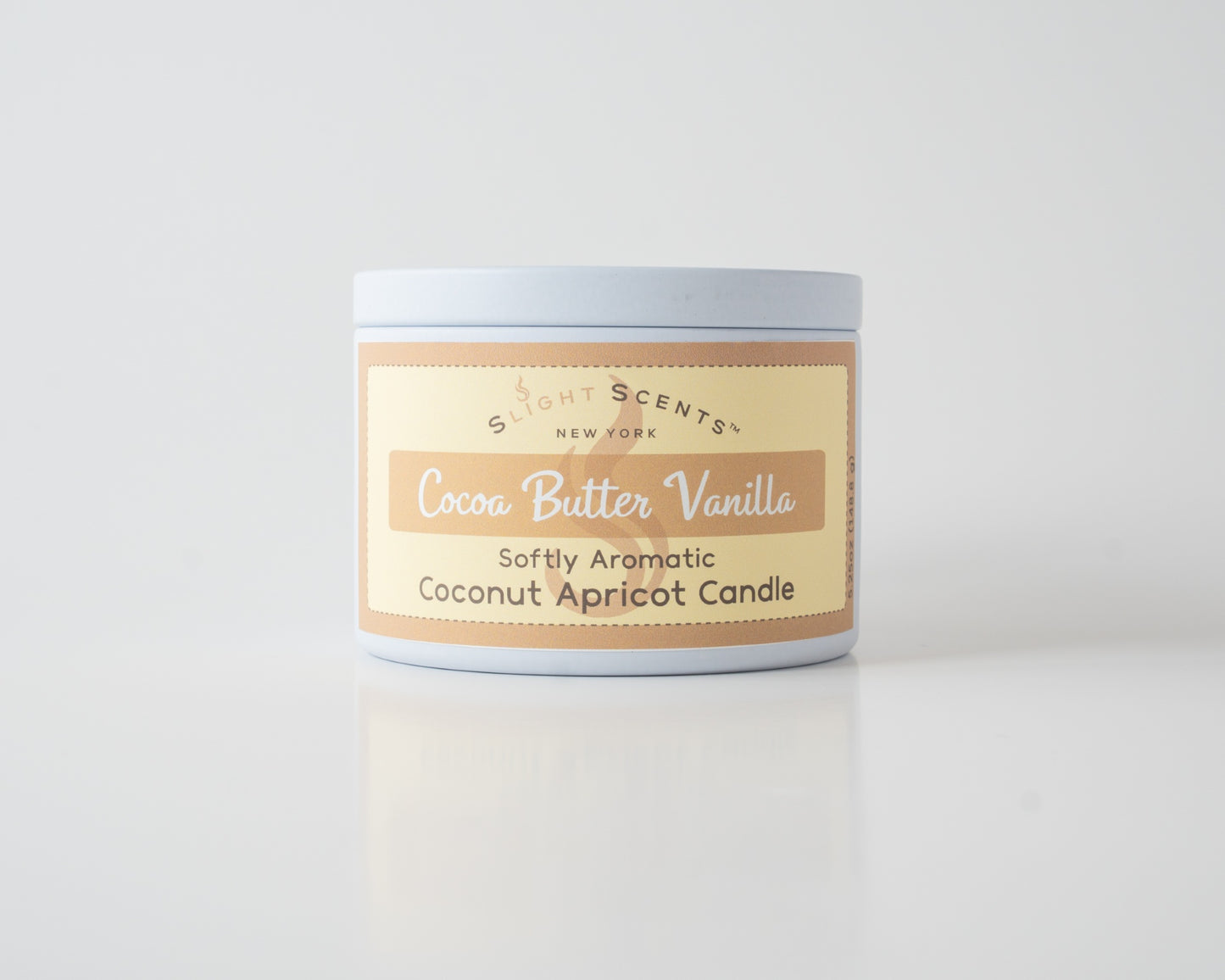 Cocoa Butter Vanilla Coconut Apricot Candle By Slight Scents New York in a white metal tin on a white background.
