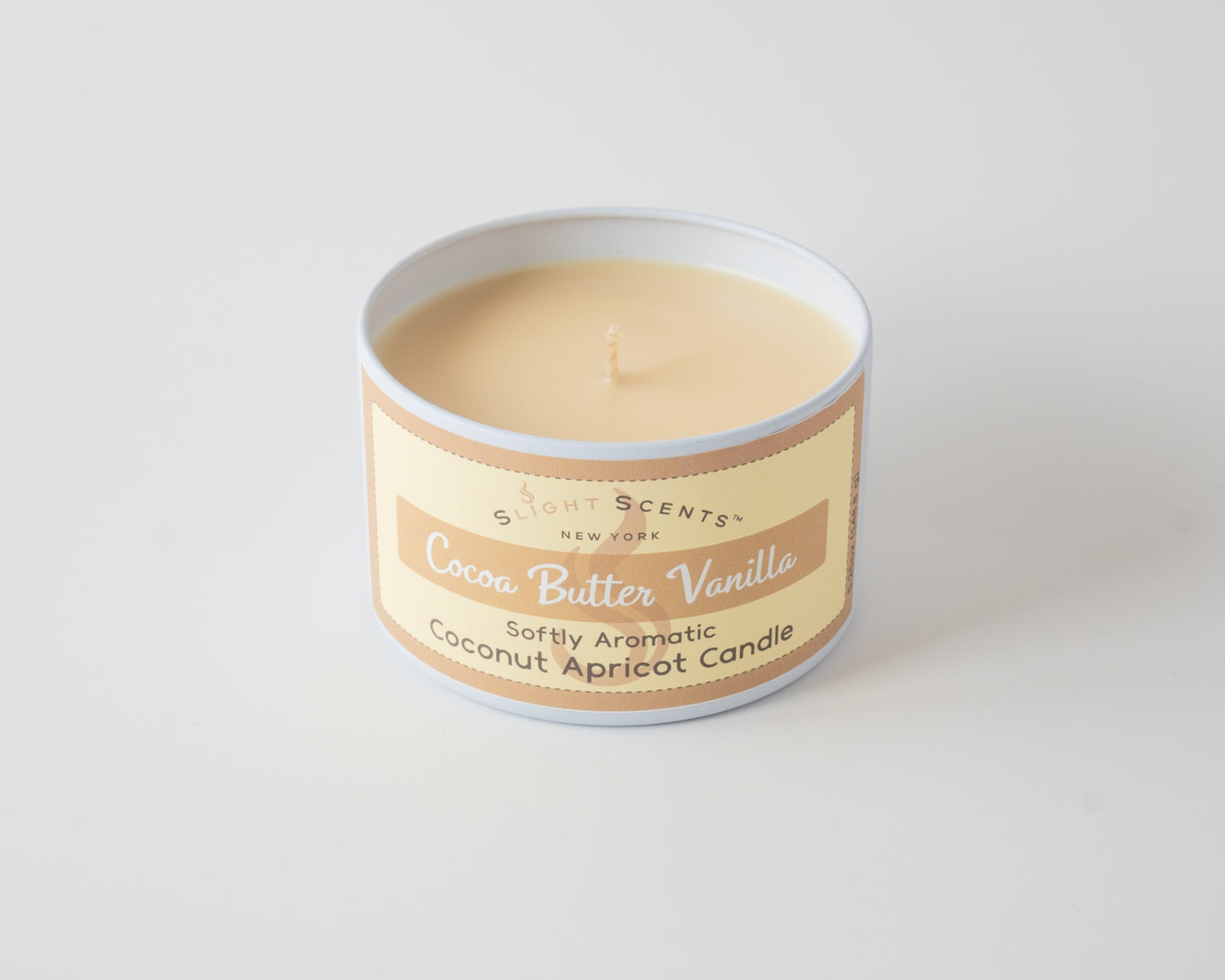 Cocoa Butter Vanilla Coconut Apricot Candle By Slight Scents New York in a white metal tin on a white background without a lid.
