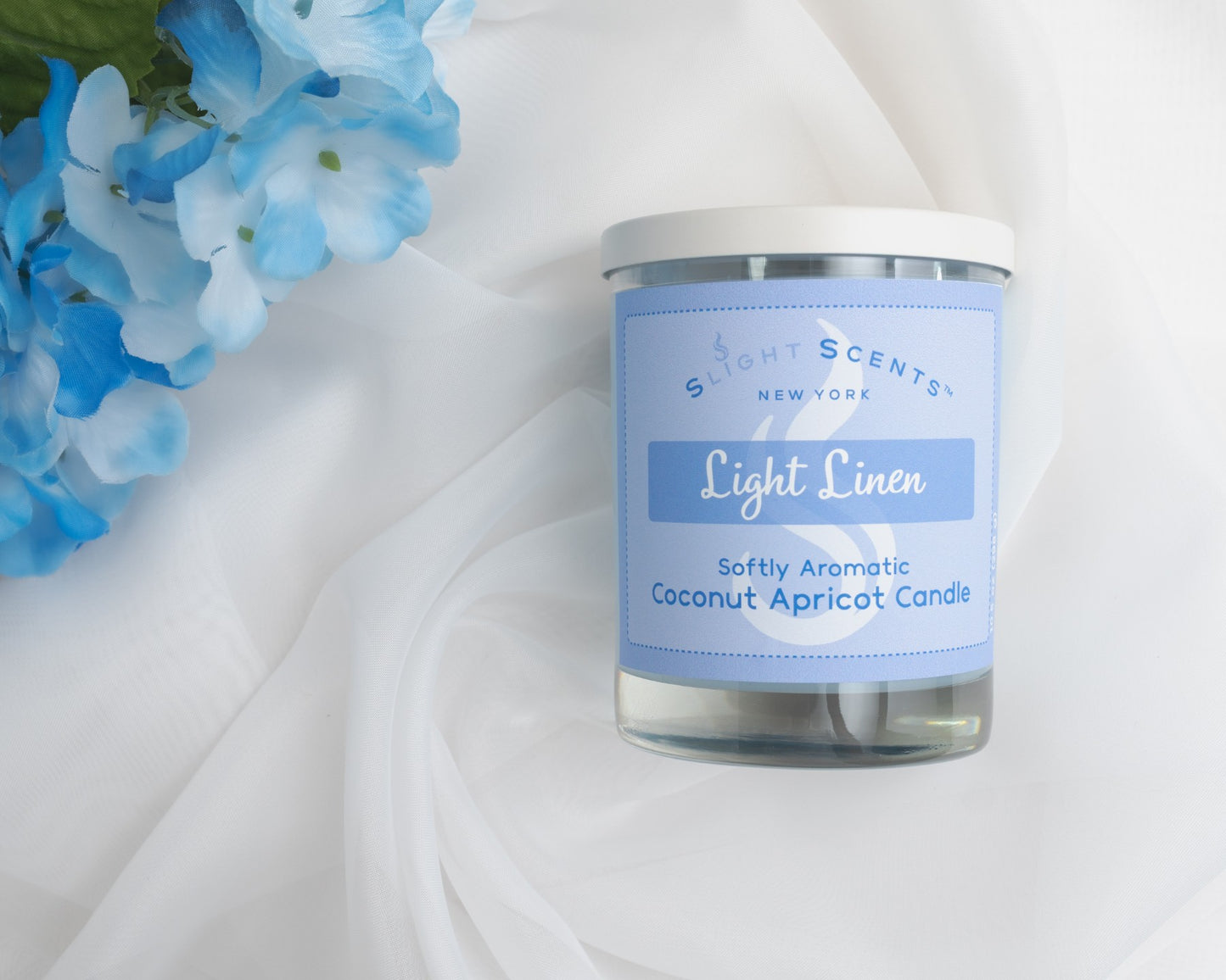 Candle labeled 'Light Linen' by 'Slight Scents New York' with blue flowers on a white background.