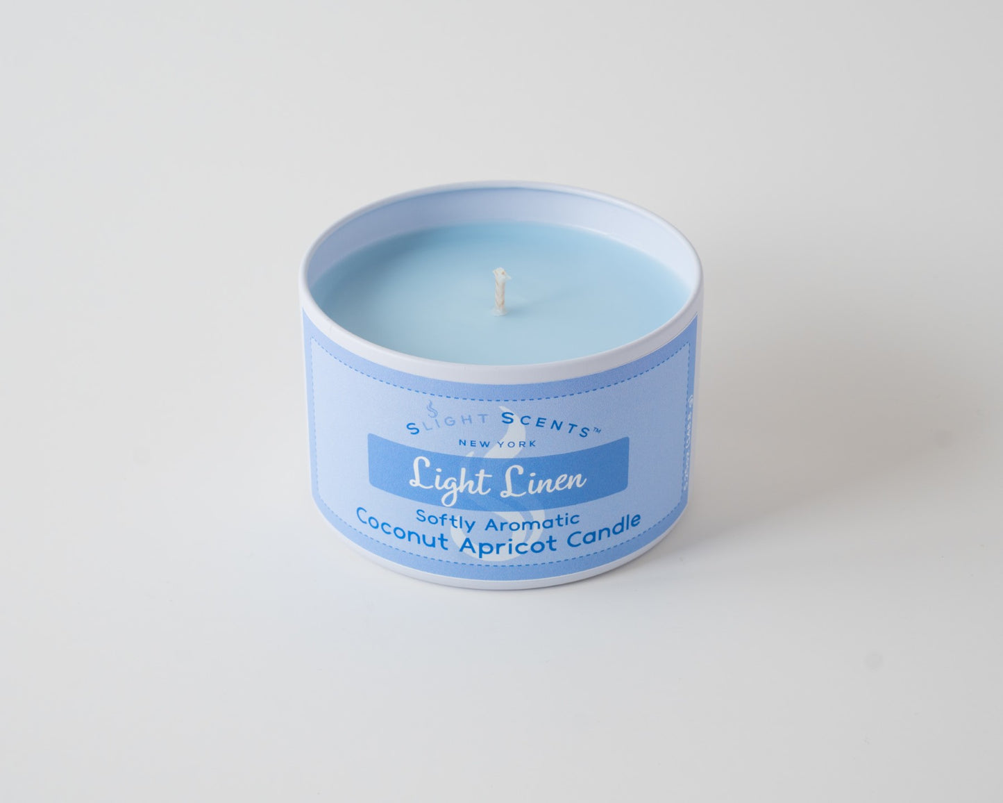 Light Linen Coconut Apricot Candle By Slight Scents New York in a white metal tin on a white background without a lid.