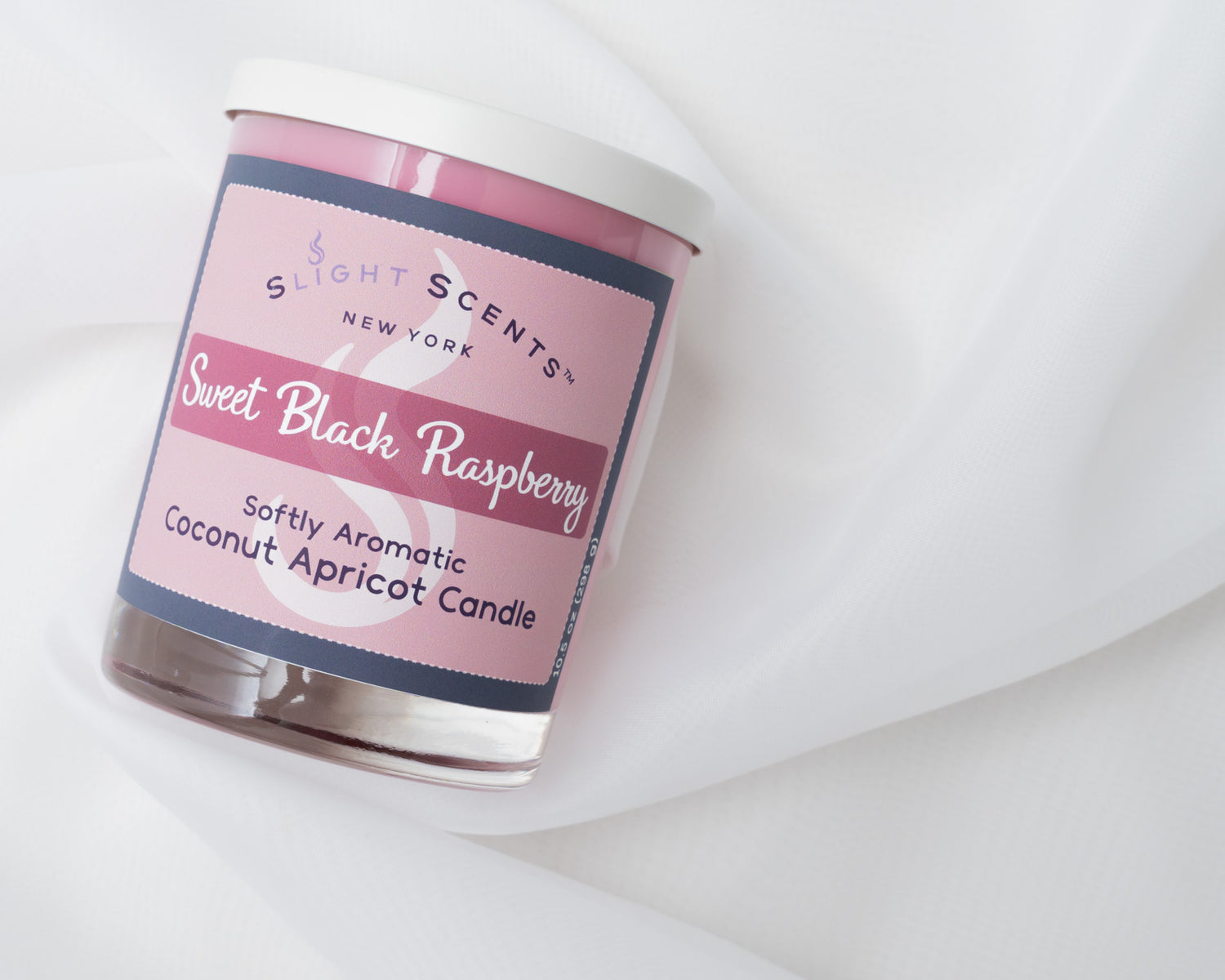Sweet Black Raspberry candle laying on its side on a white cloth.