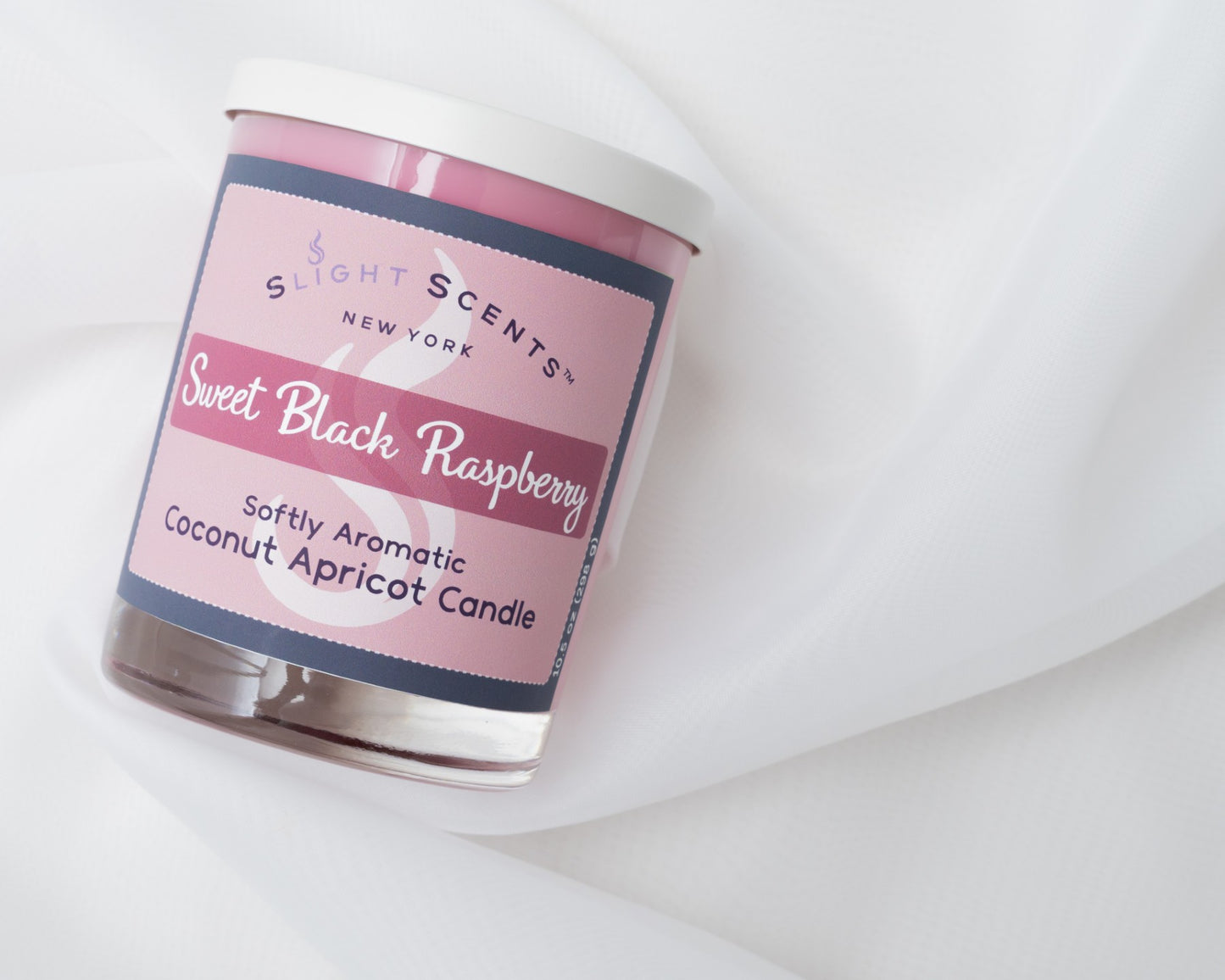 Sweet Black Raspberry candle laying on its side on a white cloth.