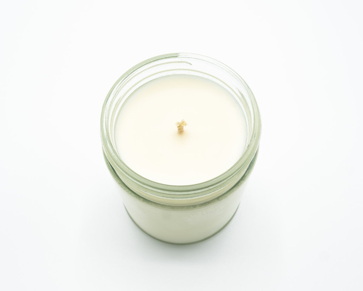 A single-wick jar candle with creamy off-white soy wax in a clear glass jar, photographed from a top-down angle on a seamless white background.