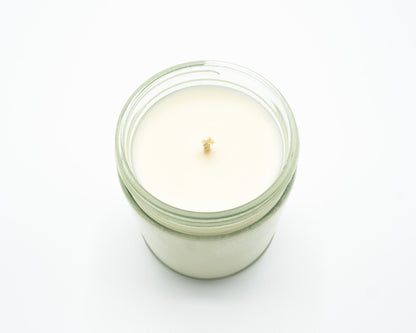 A single-wick jar candle with creamy off-white soy wax in a clear glass jar, photographed from a top-down angle on a seamless white background.