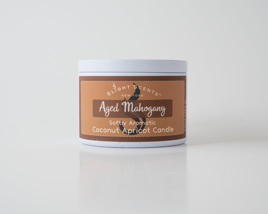 Aged Mahogany Coconut Apricot Candle By SlightScents New York in a white metal tin on a white background. 
