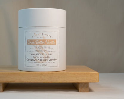 White candle tube container for Slight Scents New York featuring the fragrance Cocoa Butter Vanilla with notes of warm spices, vanilla tonka, jasmine, coconut, cedarwood, sandalwood, amber, cocoa butter, and musk. Softly Aromatic coconut apricot candle, 10.5 oz, with a burn time of 50+ hours. Handcrafted in Ossining, NY.