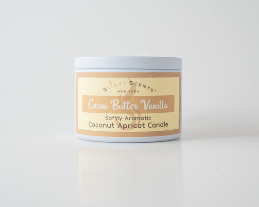 Cocoa Butter Vanilla Coconut Apricot Candle By Slight Scents New York in a white metal tin on a white background.