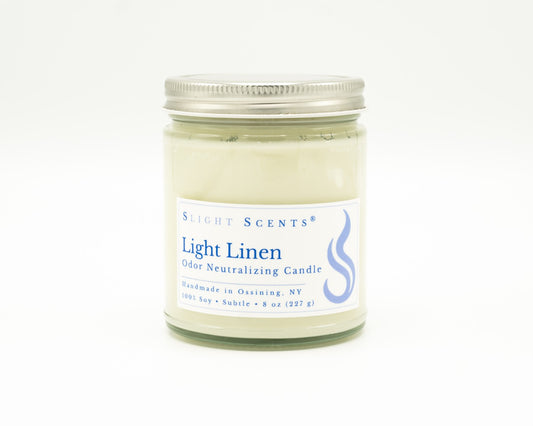 Front view of an Light Linen odor neutralizing candle with white label, undyed wax, and silver metal lid in a glass jar. 