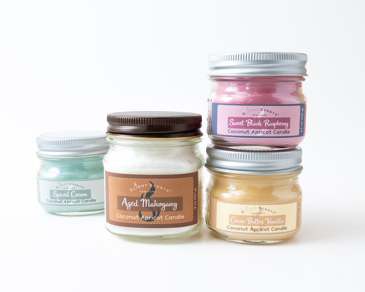 4 and 8oz Slight Scents mason jar candles stacked on one another. Scents shown are Spiced Cream, Aged Mahogany, Sweet Black Raspberry, and Cocoa Butter Vanilla.