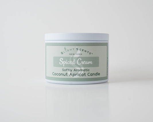 Spiced Cream Coconut Apricot Candle By Slight Scents New York in a white metal tin on a white background.