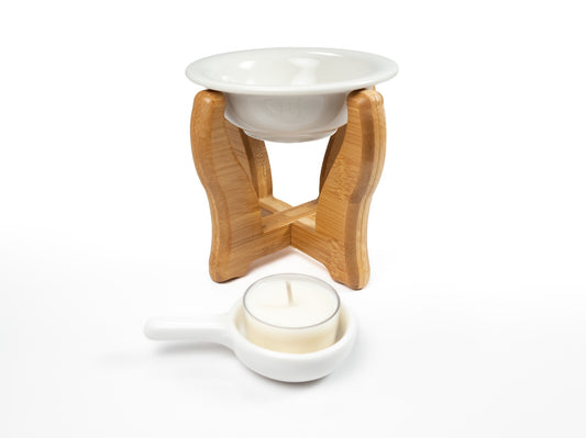 A bamboo wax warmer with the ceramic bowl placed on top of the frame, while the ceramic tealight holder with a tealight candle is positioned in front of the frame. The setup showcases the components of the warmer, including the natural bamboo frame, ceramic bowl for wax melts, and the matching tealight holder with its handle.